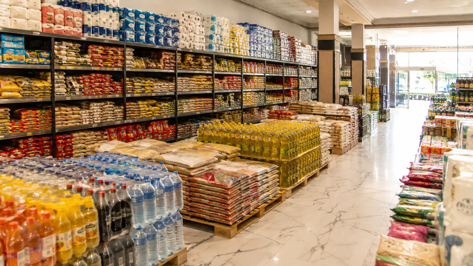 Bora Toptan & Perakende mağaza içi — dolu raflar ve palet üstü toptan ürünler